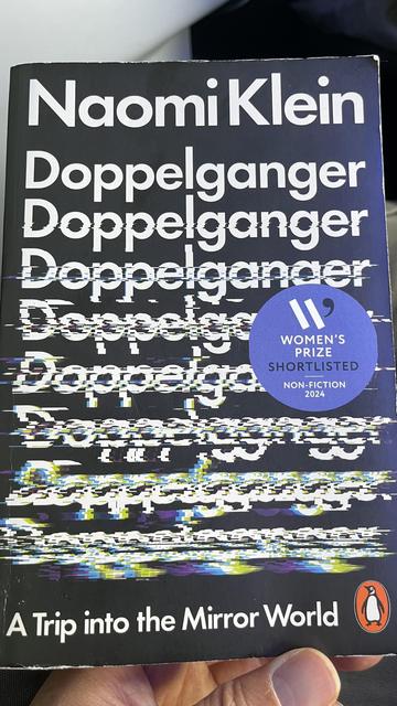 The image features the cover of the book "Doppelganger" by Naomi Klein. The title is prominently displayed in multiple lines with a distorted design. A circular blue sticker states "Women's Prize Shortlisted 2024".
