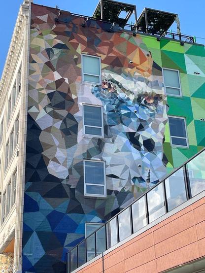 Detail of street art on the side of a building: a cubic abstract of a face, possibly a gorilla.