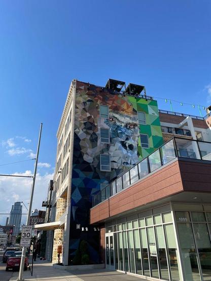 Street art on the side of a building: a cubic abstract of a face, possibly a gorilla.