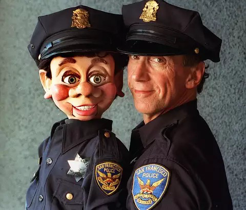 The dummy Brendan O'Smarty and his human partner Bob Geary in a publicity shot, both in their police uniform, including badge and cap