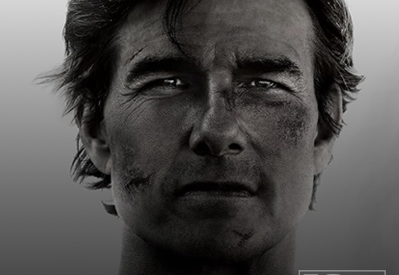 Grim and grimy-faced Tom Cruise straight to camera in black and white. The things he's seen . . 