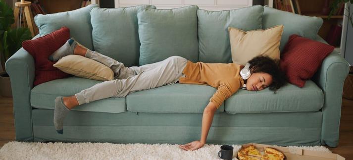 Una joven tumbada en el sofá sin trabajar ni estudiar. / stockphotodirectors