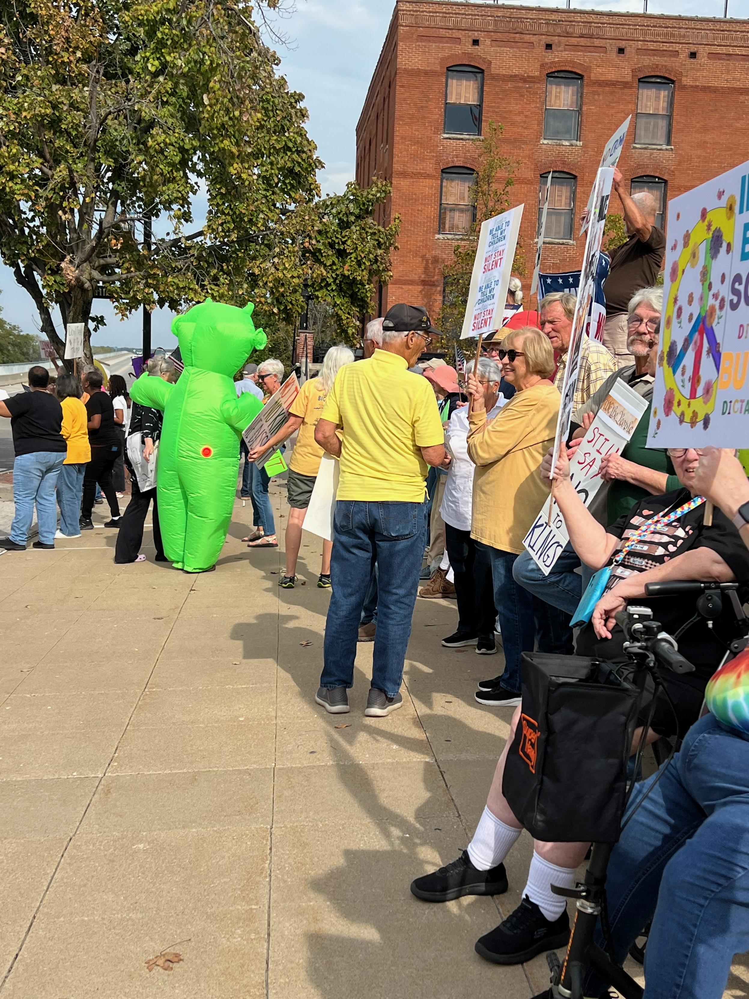 A group of protestors holding No Kings signs along a sidewalk.