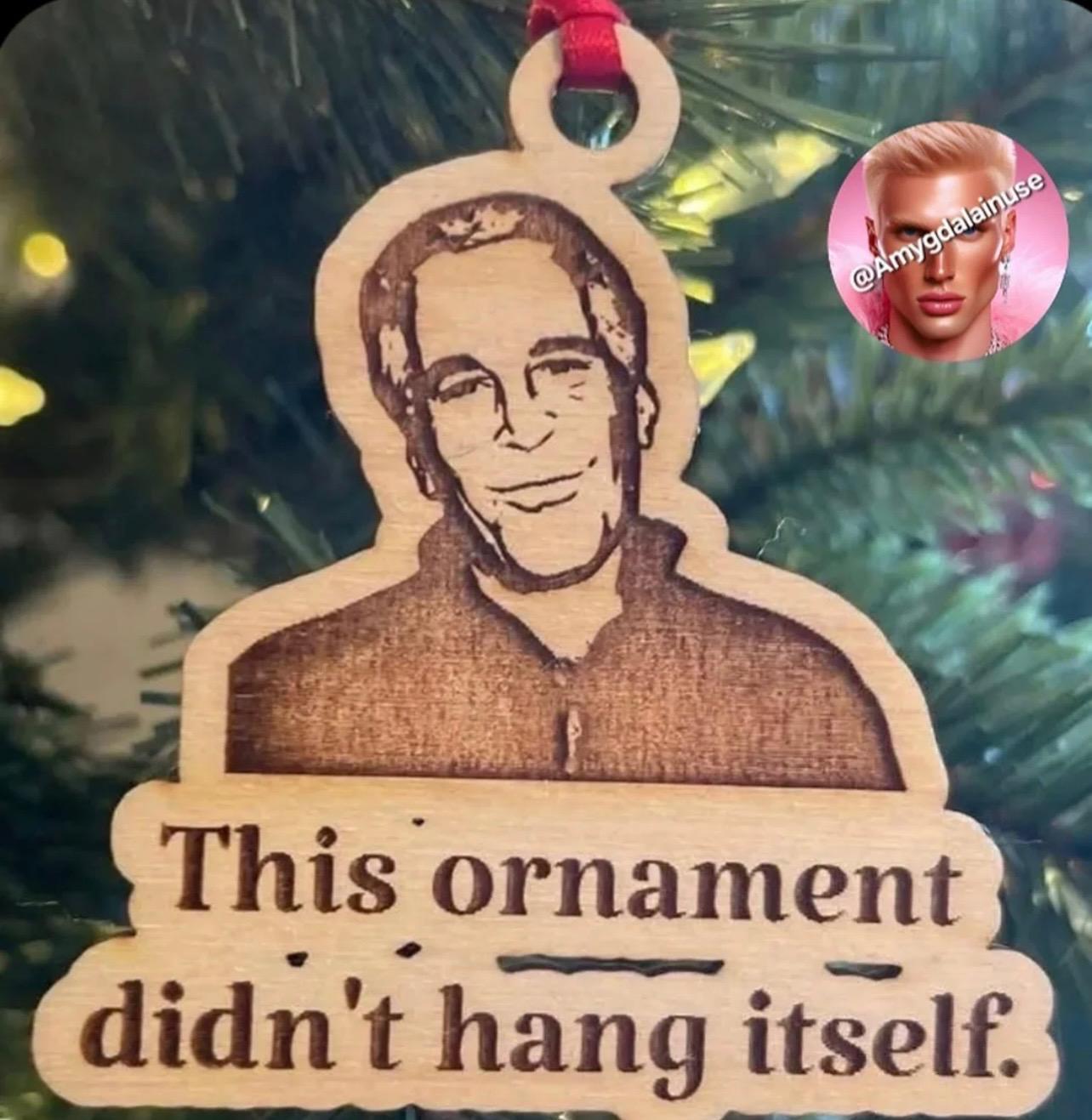A Christmas ornament with a drawing of Jeffrey Epstein and a text underneath reading “This ornament didn’t hang itself.”