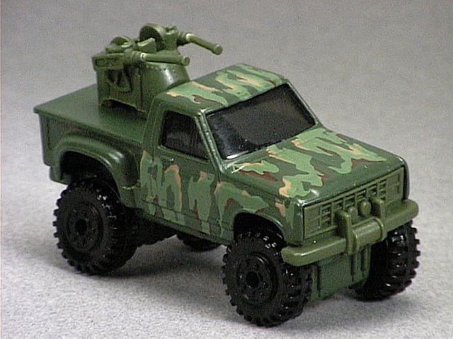Released in 1987, Olive Tail Gunner of 1987 Hot Wheels with Construction Tire wheels. Notes: Customized Ford pickup truck with two olive plastic guns in back. Tampo: Green, tan and brown camouflage on top and sides. Packaging: Action Command(r). Metal Body, Metal Base. Made in Malaysia. Scarcity: 2/10