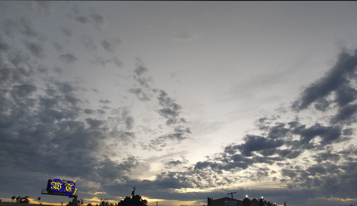 the sun has set but still shines a yellow glow behind streaks of fluffy grey storm clouds.

my logo, WT7 is posted over a billboard in the skyline