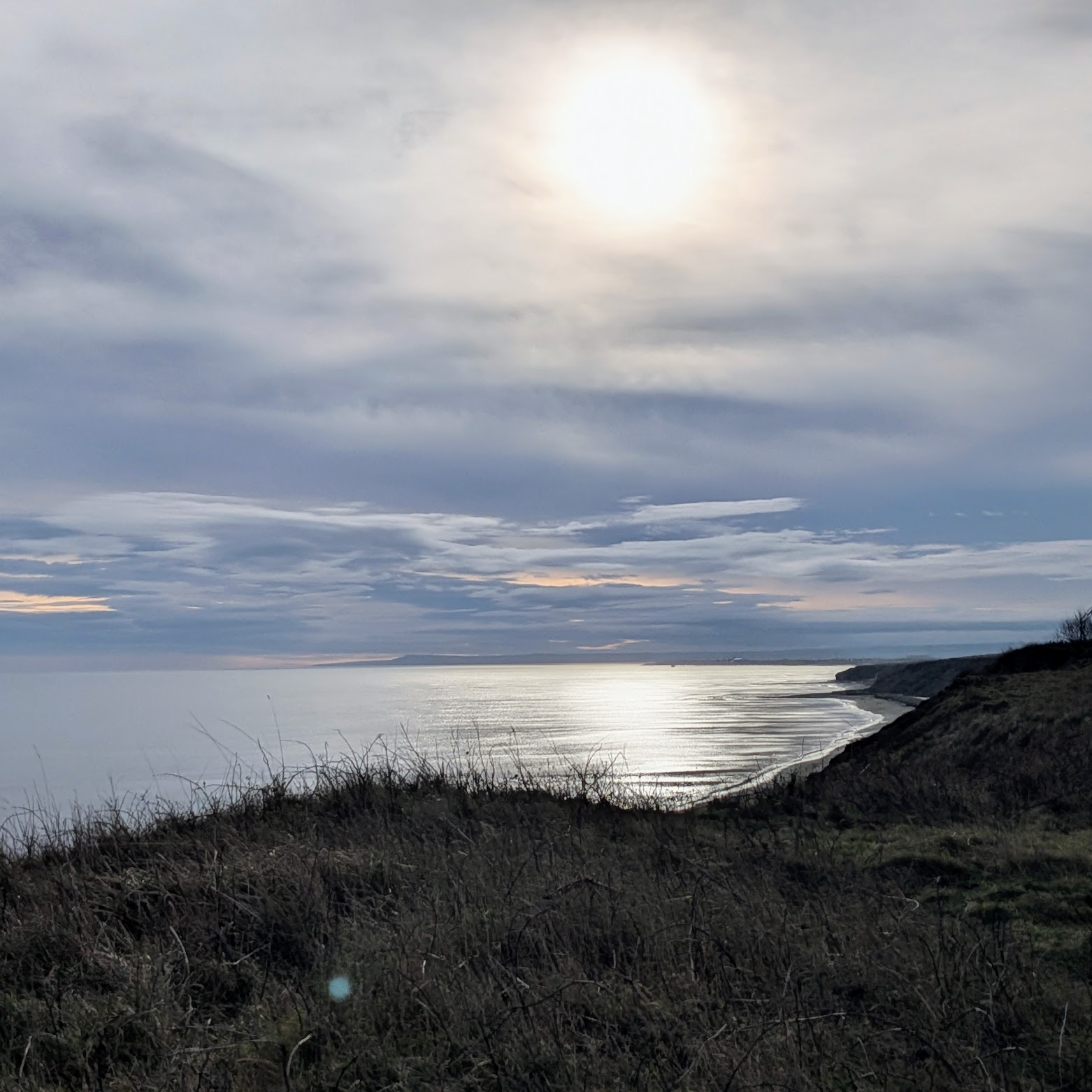 A photograph of a cloudy sky over the sea and beach at Cotsford Fields in NE England.