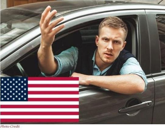 Man gesturing angrily from a car window.