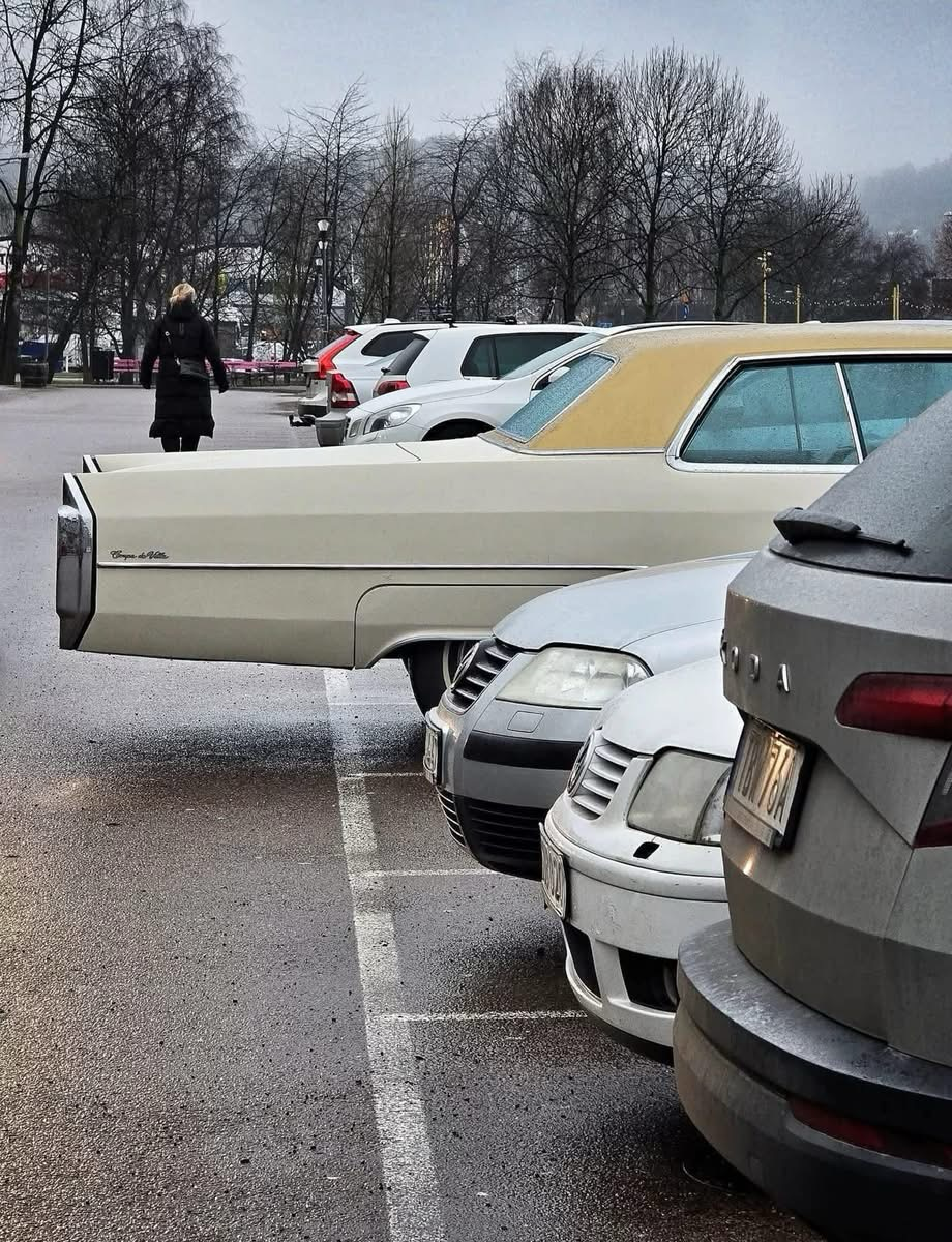Cars parked neatly between the lines with a 70’s era Cadillac overhanging past the line by over two feet
