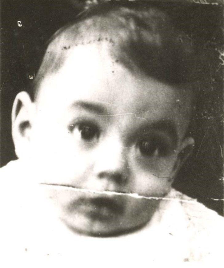 A photo of a baby boy's face. He has wide eyes and short dark hair.