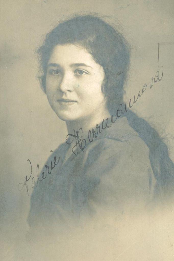 A portrait ID-style photo of  a young woman with dark, long hair falling on her back. Handwritten signature is visible in the photo.