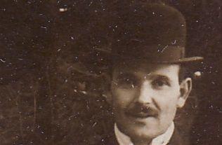 A man wearing a bowler hat with a slight smile in an old-fashioned.