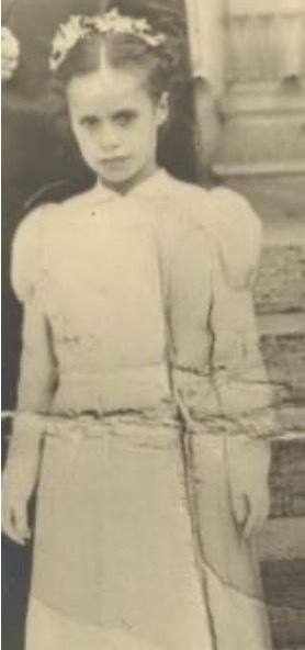 Vintage photo of a young girl in a formal dress with flowers in their hair.
