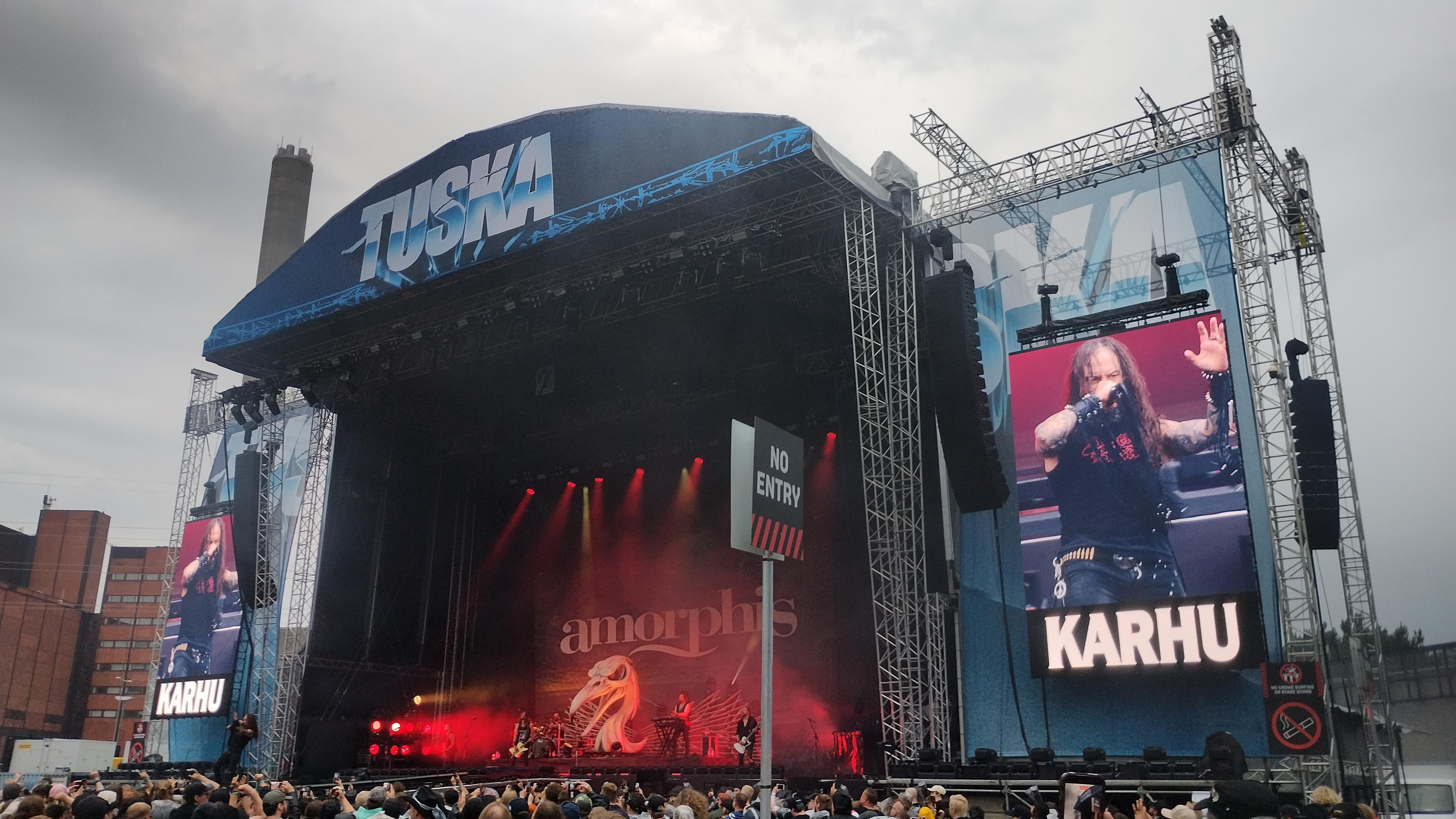 A photo of the main stage at an open air metal festival. Above the stage, the event name Tuska. To the sides, big screens showing lead singer Tomi Joutsen. In the centre - if you zoom in a bit - the actual band.