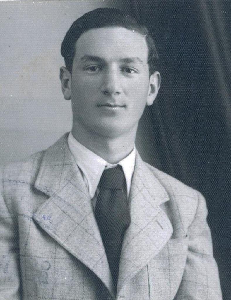 Black and white portrait of a young man in a checkered suit and tie,