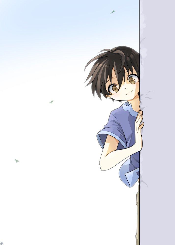 A dark-haired boy is looking around the corner, directly at you. He has a very friendly expression.