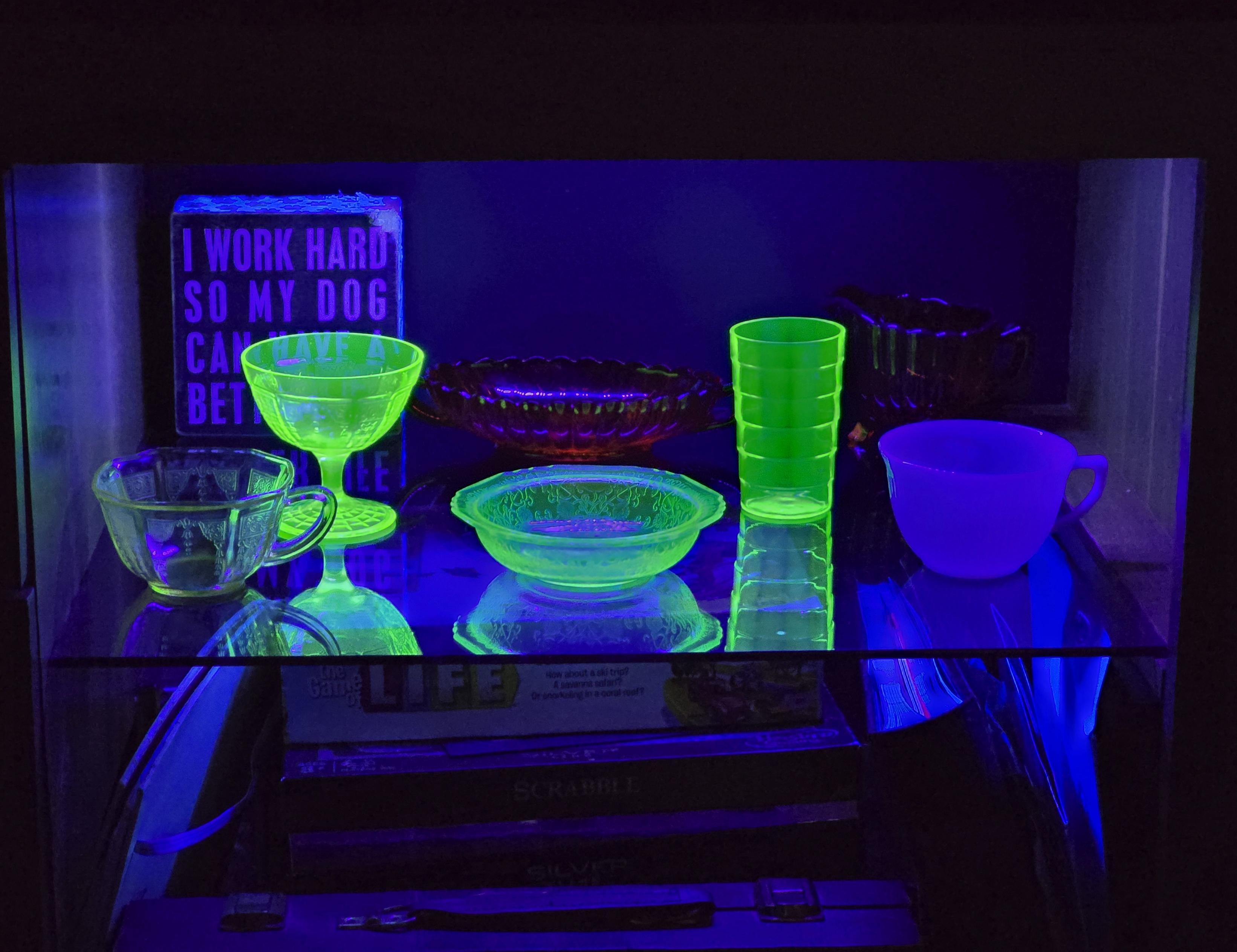 A case displaying various pieces of antique glass, a mix of cadmium, manganese and uranium in a blacklight.