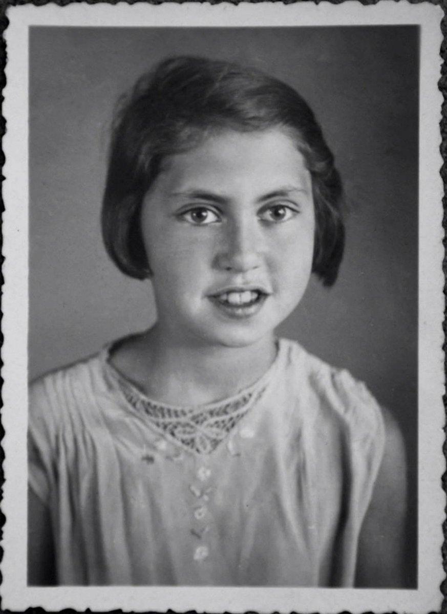 Vintage black and white portrait of a young girl with an earnest expression, wearing an embellished blouse.