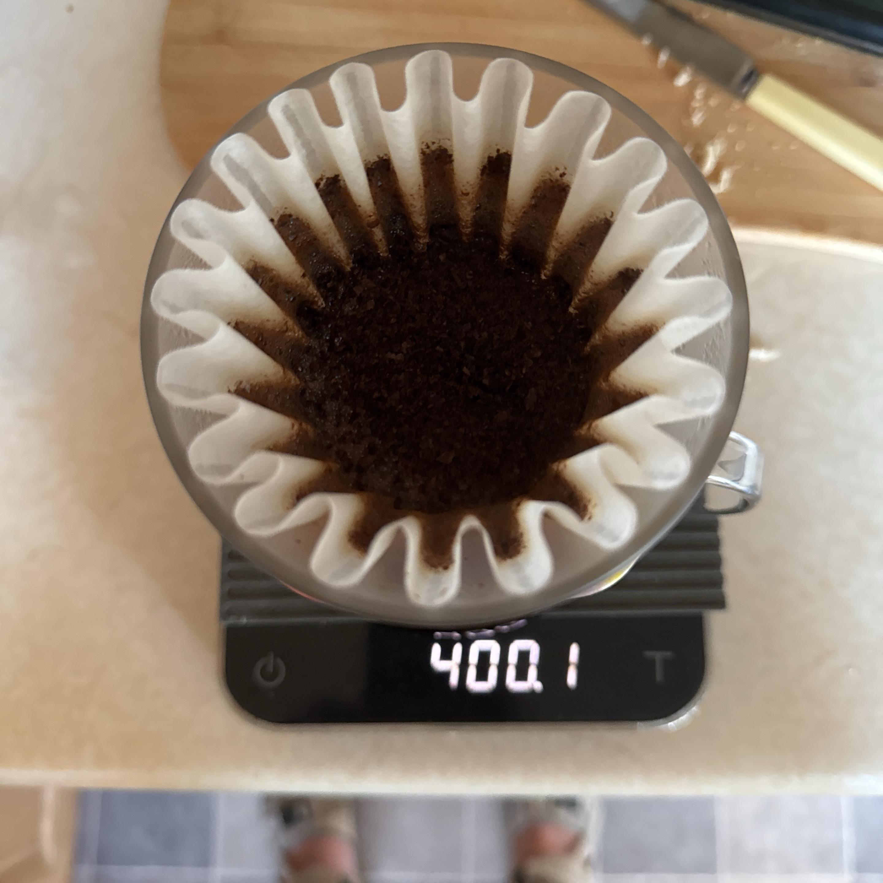 A top-down view of a coffee brewing setup, featuring Oreo and a wave coffee filter with ground coffee inside it, placed on a digital scale displaying 400.1 grams.