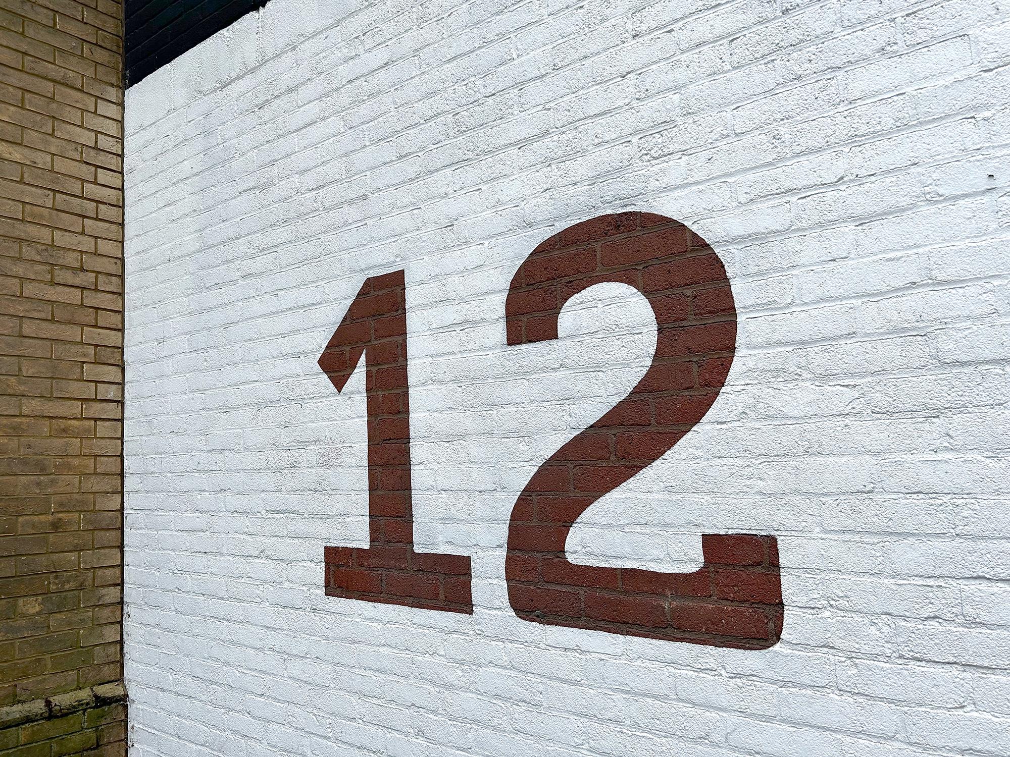 A redbrick wall has been painted white, except for two large numerals—its street number. 12 Forbury Road, Reading, Berkshire, UK. Photo by Gearóid Burke.