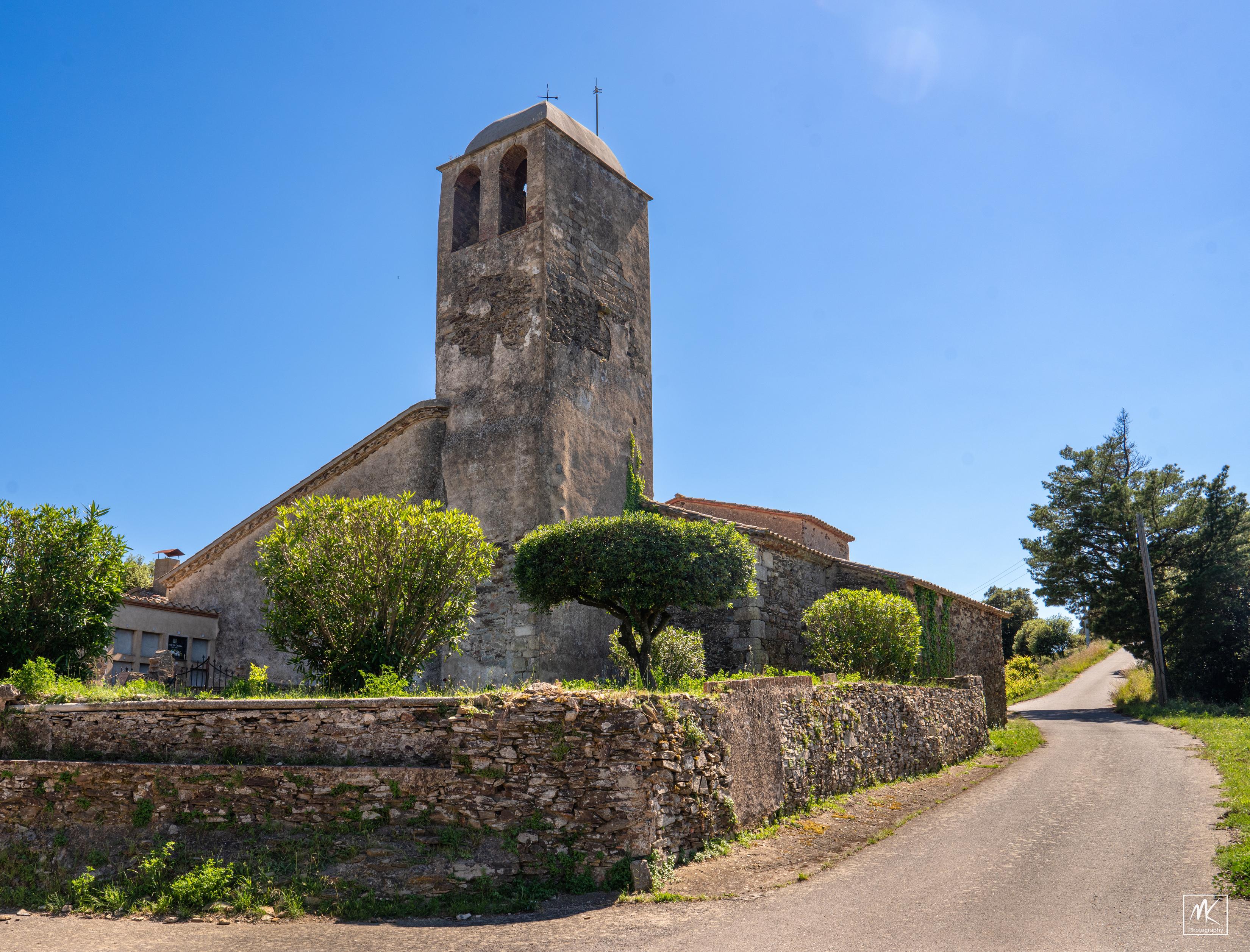 Color photo of an old rural Catalan stone church with a tall square bell tower.