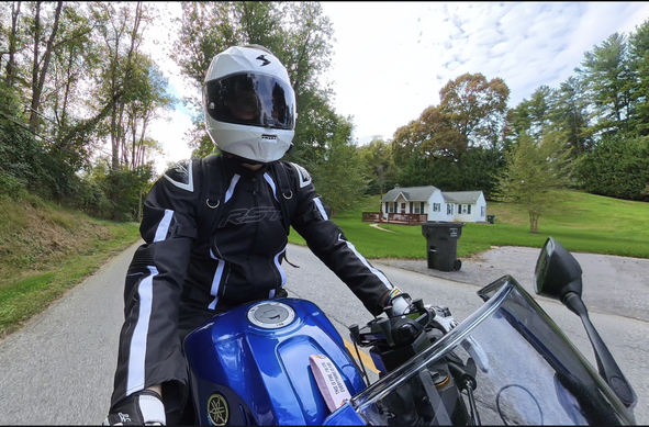 A guy in black motorcycle gear and a white helmet riding a blue Yamaha R3, as seen from a front-mounted camera