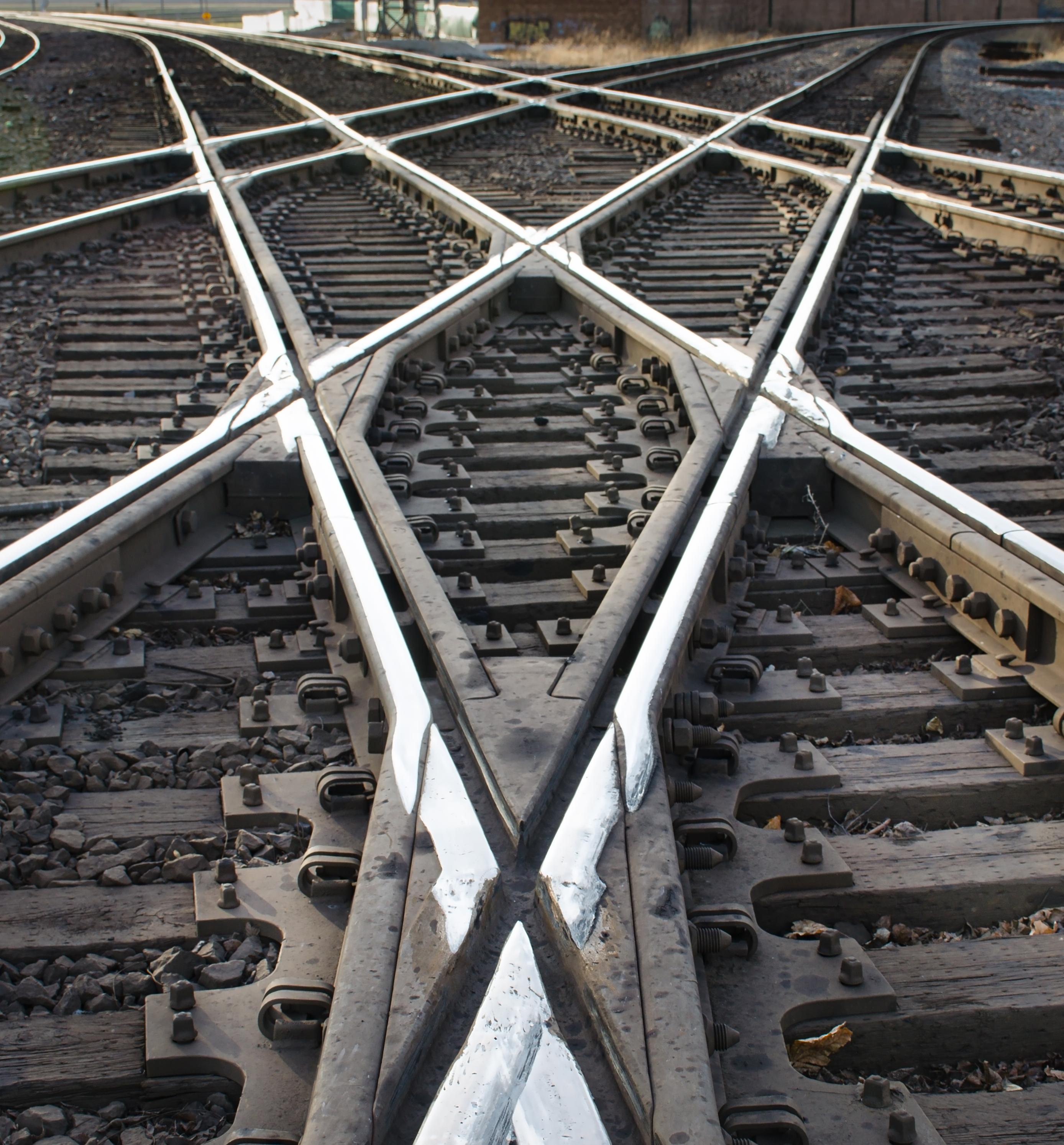 Union Pacific and BNSF main line crossing. The tracks form two different vanishing points. Special sections of steel with dozens of bolts hold the rails in place.