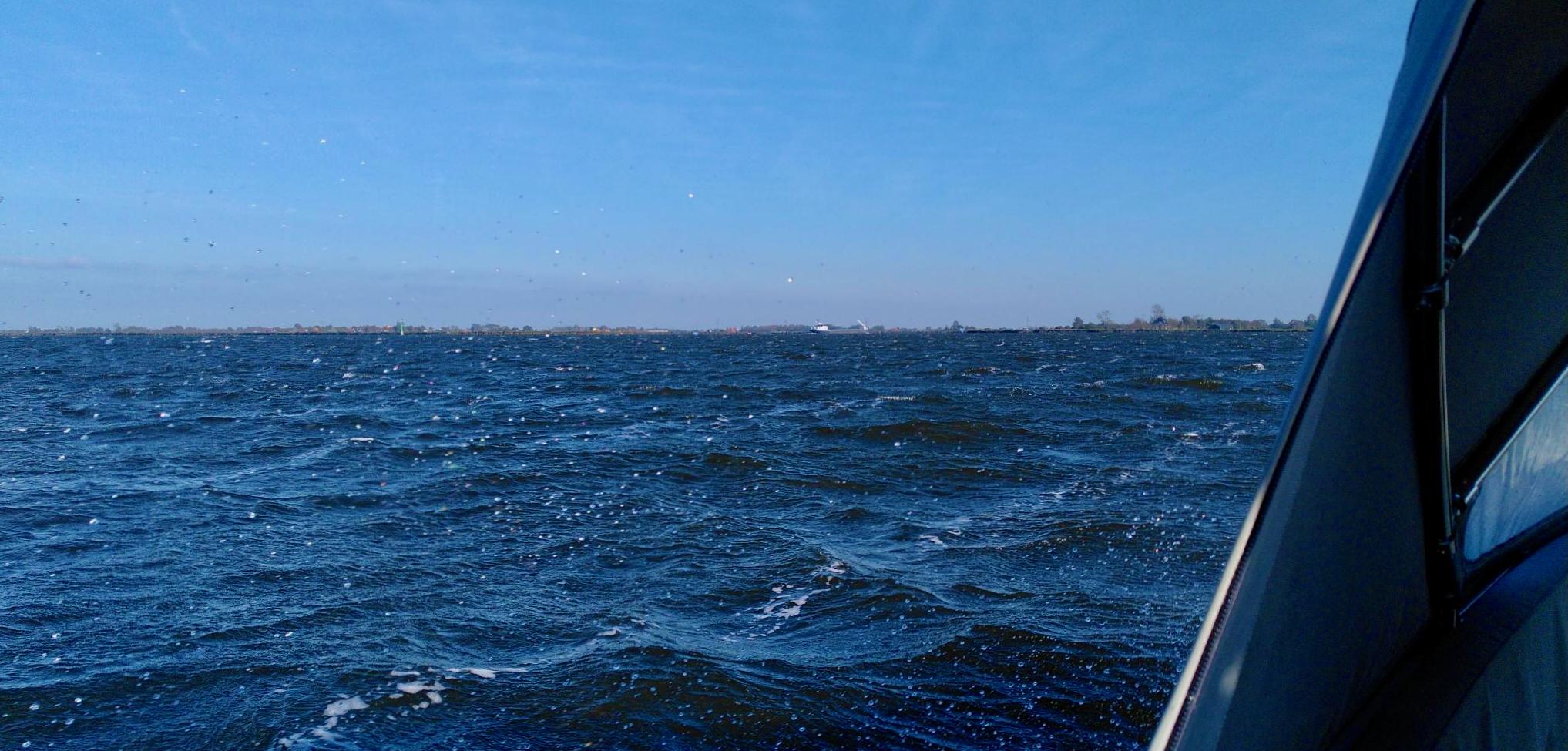 The view from the port side across a rugged sea of waves and the spray from the breakers crashing against the hull.