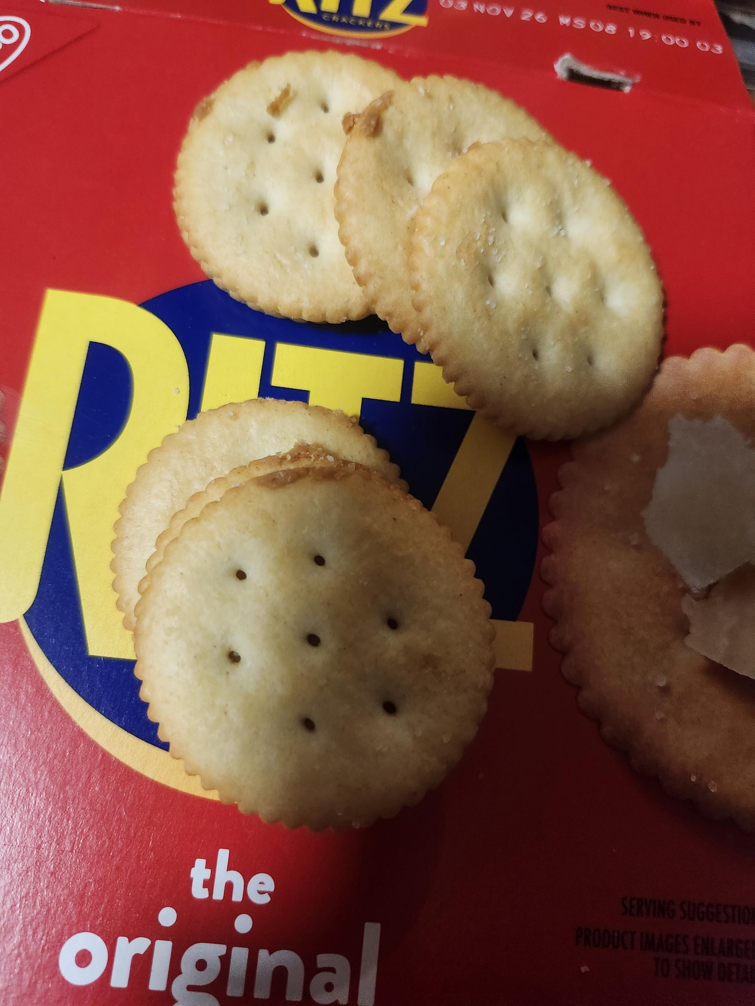 A few Ritz crackers on the box showing peanut butter on the edges