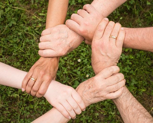 Hands holding onto wrists of others, uniting.