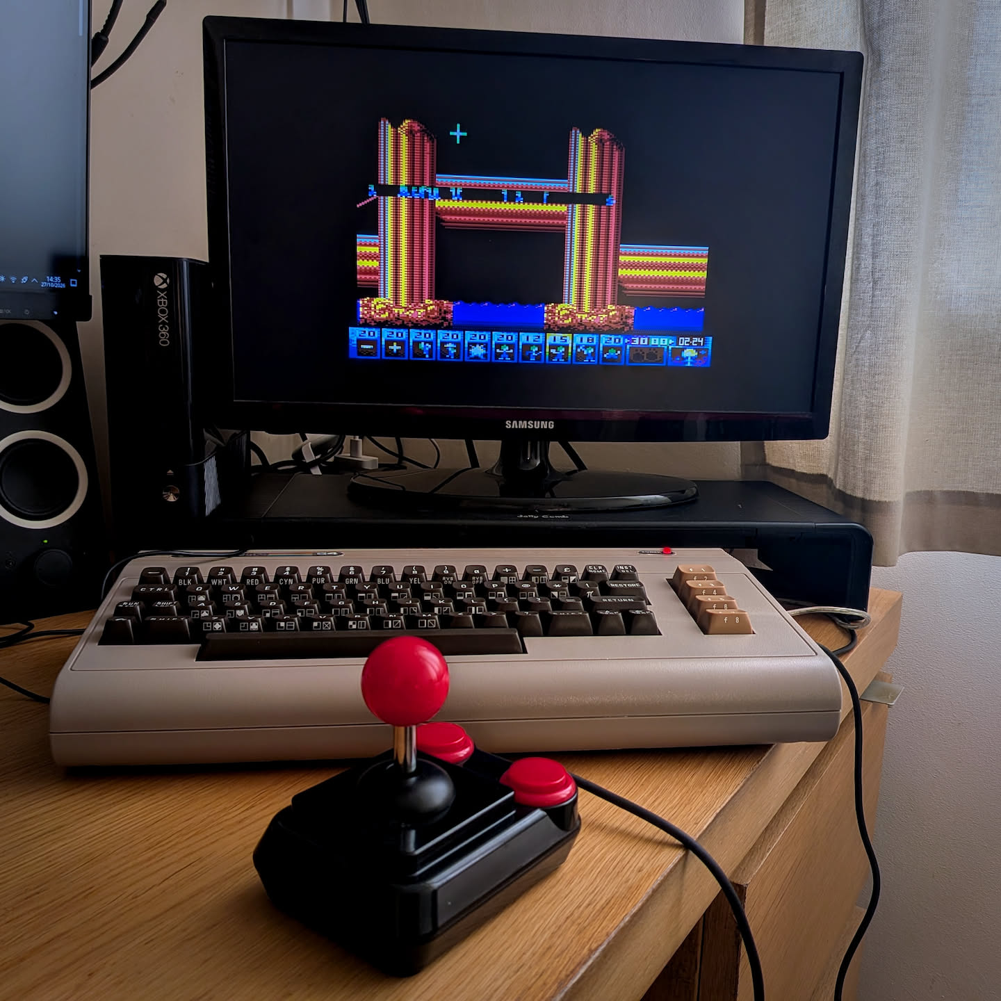 A photograph of a Commodore 64 Ultimate playing Lemmings Reloaded with an old fashioned Arcade-R joystick in the foreground.