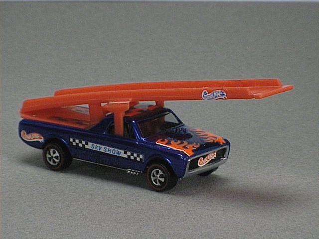 Released in 1970, Spectraflame Blue Sky Show Fleetside of 1970 Hot Wheels with Redline wheels. Notes: Only available in the Flying Circus set or Sky Show set. Comes with a red ramp on the bed, and yellow plastic plane. Tampo: Black and white checker sticker on sides that has blue 'Sky Show' in the middle. Packaging: 1970 Blister. Metal Body, Metal Base. Made in USA. Scarcity: 7/10