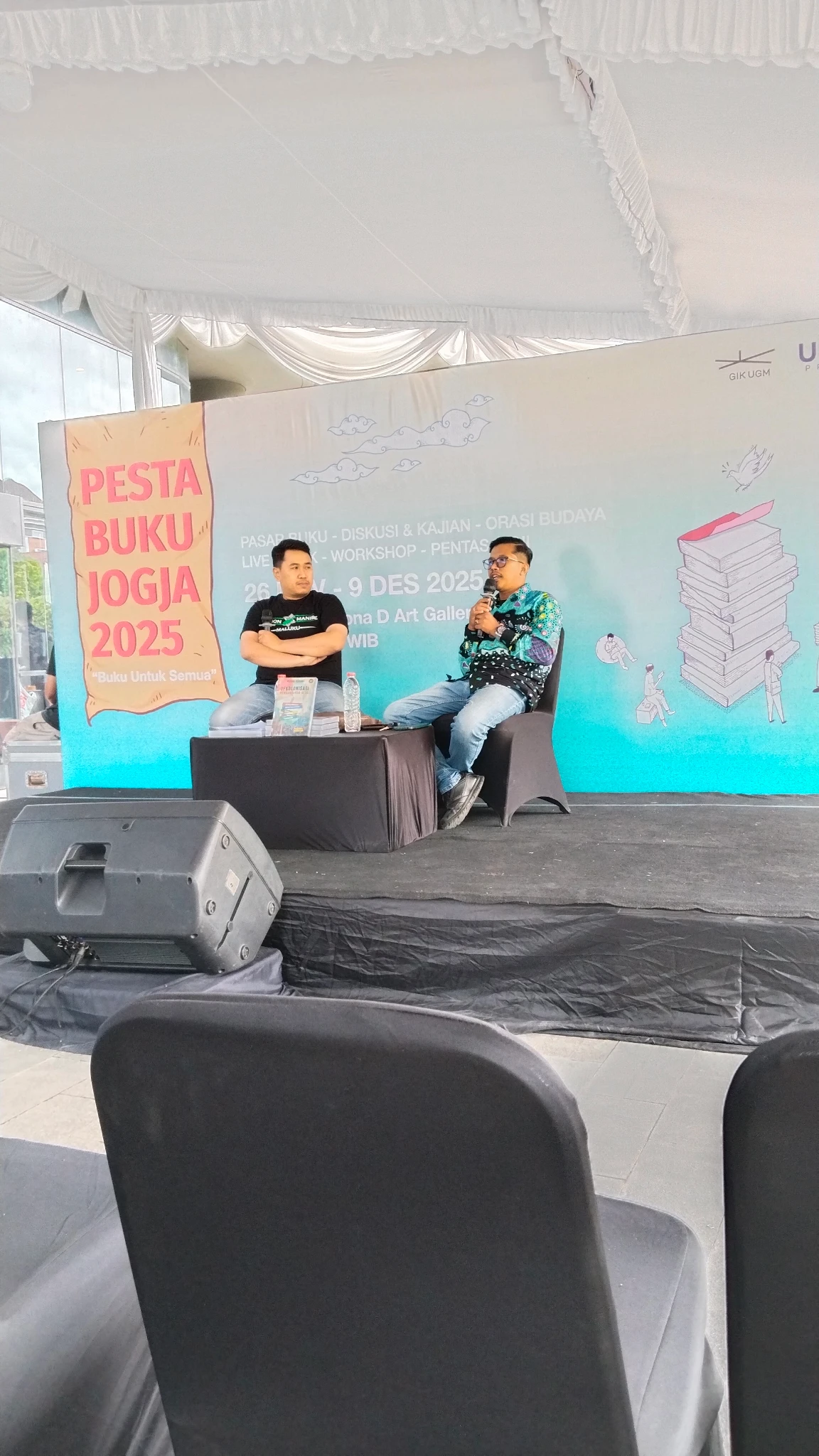 Dua orang duduk di atas panggung