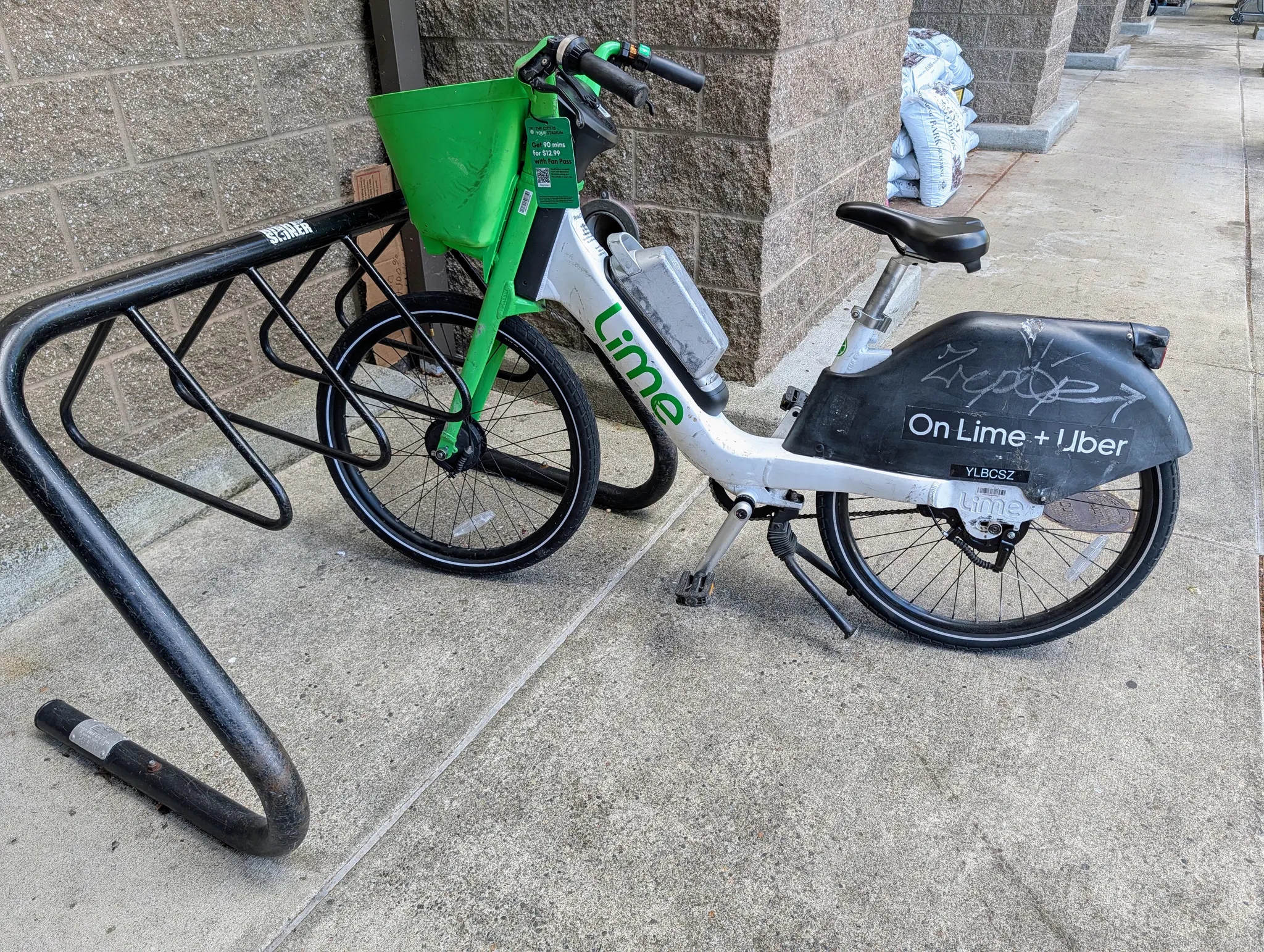 A Lime e-bike parked at the cycle rack in front of Safeway, taking up space